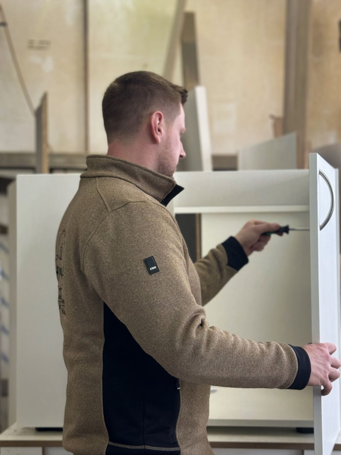 Ein Mitarbeiter schraubt ein Holzregal zusammen